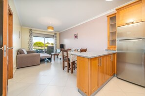 Une cuisine moderne avec des meubles en bois, un réfrigérateur encastré et un coin repas comprenant une table et des chaises.