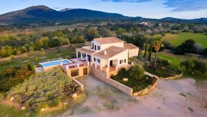 A two-story house with a swimming pool, surrounded by a landscaped garden and a hilly landscape. - Sa Figuera – Extraordinary Villa with Mountain Views, Wi-Fi, and Air Conditioning (Illes Balears)