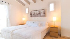 A bedroom with a large bed, two bedside tables, a wall-mounted lamp, and a window with curtains. - Sa Figuera – Extraordinary Villa with Mountain Views, Wi-Fi, and Air Conditioning (Illes Balears)