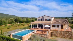 A two-story house with a swimming pool, outdoor seating, and a stone wall. - Sa Figuera – Extraordinary Villa with Mountain Views, Wi-Fi, and Air Conditioning (Illes Balears)