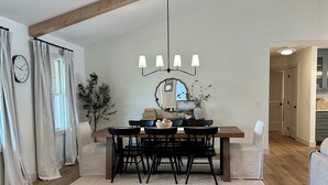 A dining area with a wooden table, black chairs, a chandelier, and a mirror on the wall. - Spacious 5-Bedroom House with Pool and Hot Tub for Families & Groups (Dundee)