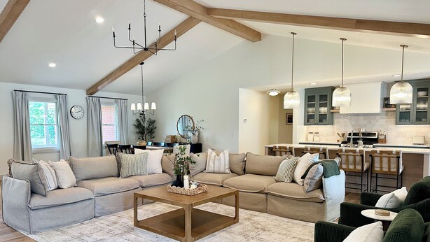 A spacious living room with a sectional sofa, a coffee table, and a kitchen area with bar stools. - Spacious 5-Bedroom House with Pool and Hot Tub for Families & Groups (Dundee)