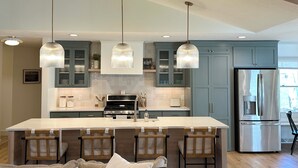 A modern kitchen with a central island, pendant lights, and stainless steel appliances. - Spacious 5-Bedroom House with Pool and Hot Tub for Families & Groups (Dundee)
