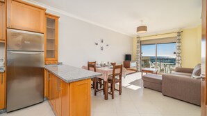 Eine moderne Küche mit Einbaukühlschrank, Holzschränken und einem Essbereich mit Tisch und Stühlen.