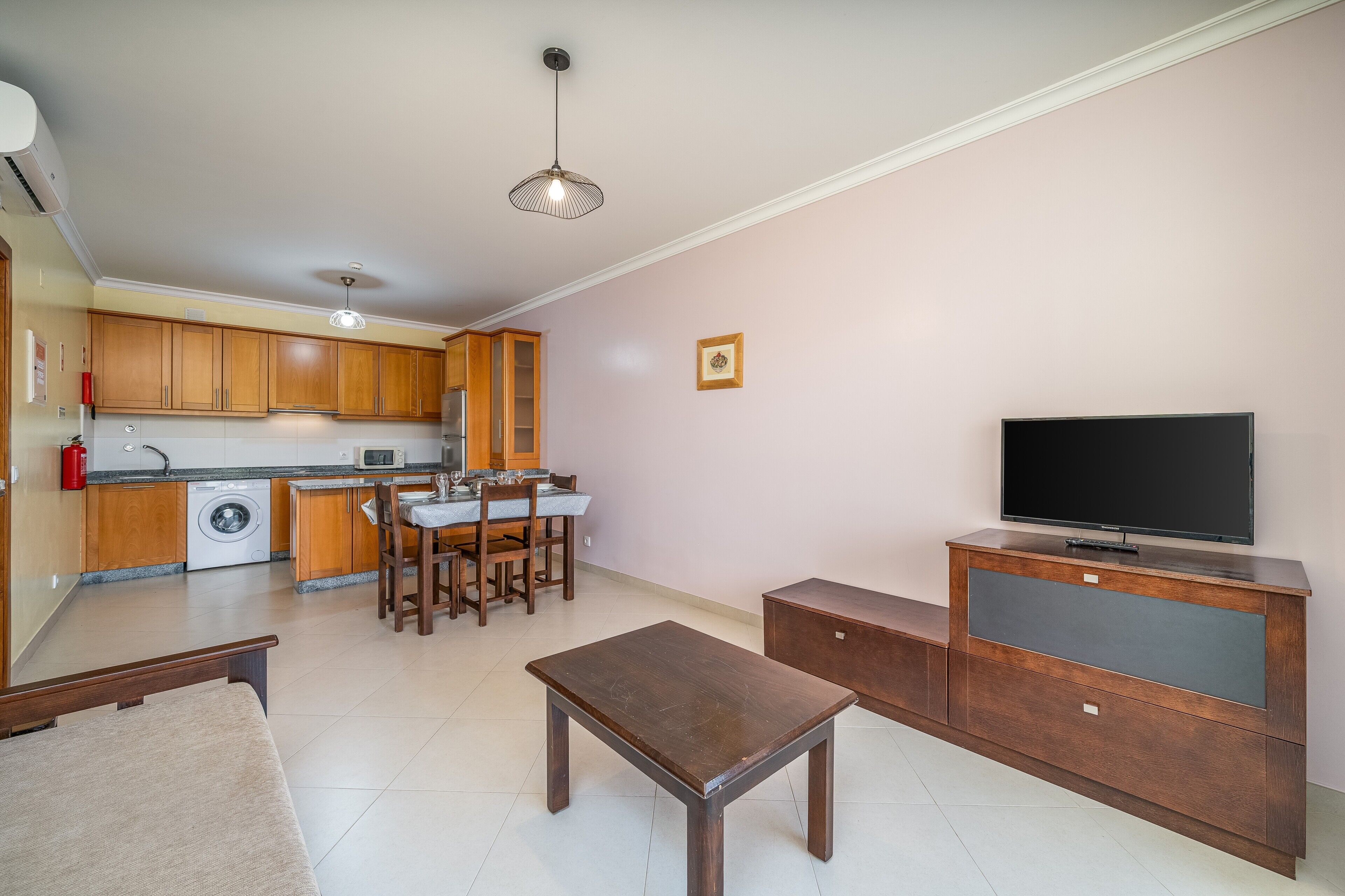 A compact living space with a kitchen, dining area, and a flat-screen TV.