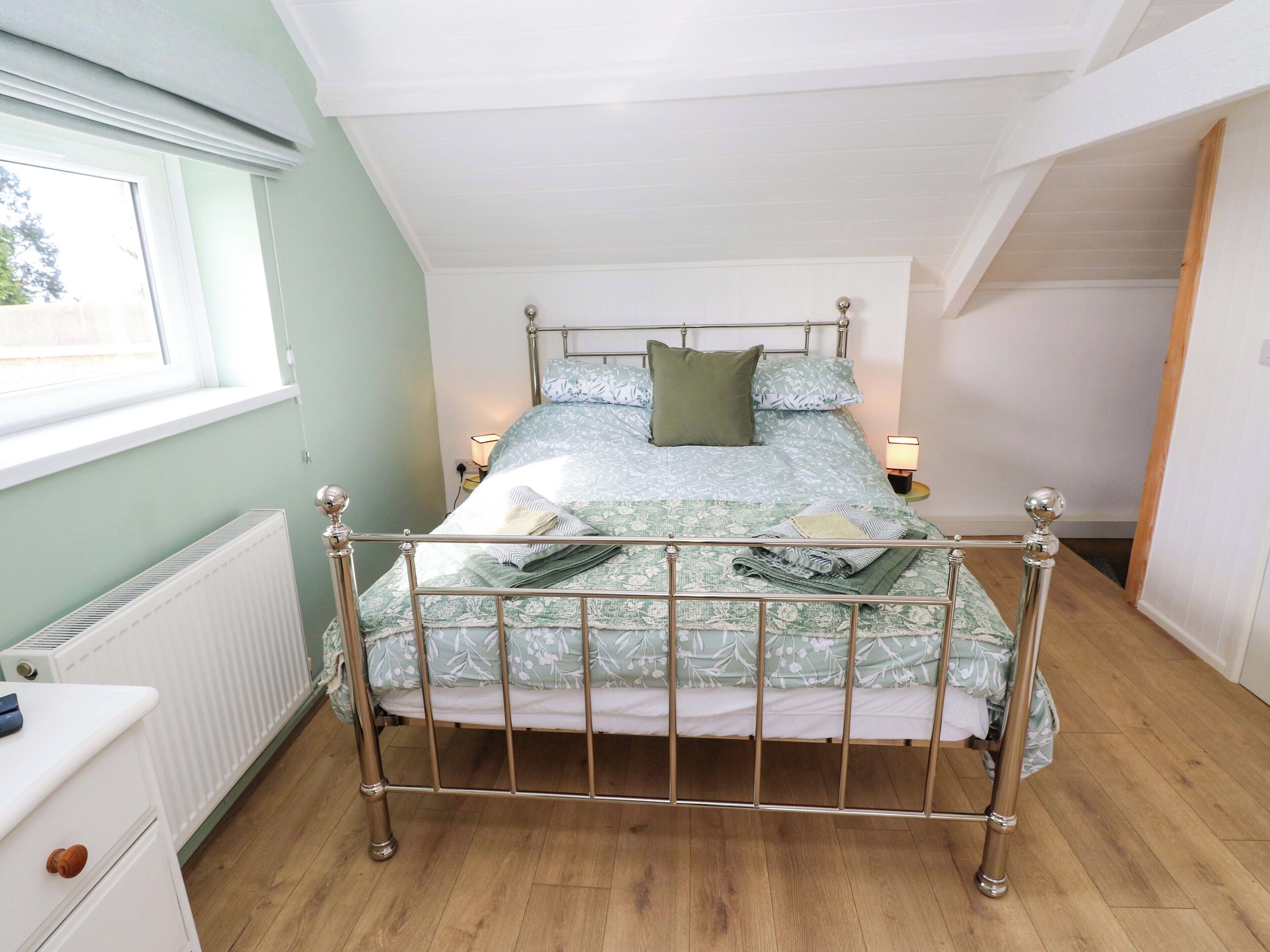 A bedroom with a metal-framed bed, a radiator, a window, and a nightstand with a lamp.