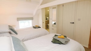 Un dormitorio con dos camas, una ventana, un espejo y una puerta que da al baño.