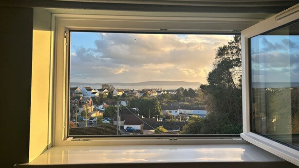 Vista desde una ventana con vistas a una zona residencial con casas, árboles y una cadena montañosa distante.