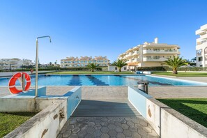 Une piscine avec une bouée de sauvetage, un ciel dégagé et des bâtiments modernes en arrière-plan.