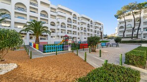 Um hotel com vários andares, varandas, parque infantil e áreas ajardinadas.