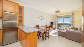 Une cuisine moderne dotée d’un réfrigérateur encastré, de meubles en bois et d’un coin repas avec une table et des chaises.