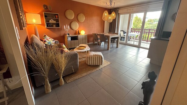 A spacious living area with a sofa, a dining table, and a balcony with a view. - Well-being apartment (Saint-Pée-sur-Nivelle)