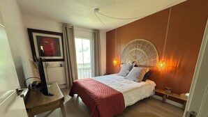 A bedroom with a bed, a desk, a chair, a window, and a wall-mounted light fixture. - Well-being apartment (Saint-Pée-sur-Nivelle)