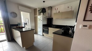A modern kitchen with a central island, built-in oven, and a refrigerator. - Well-being apartment (Saint-Pée-sur-Nivelle)