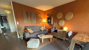 A modern living room with a grey sofa, a round coffee table, and a wooden cabinet. - Well-being apartment (Saint-Pée-sur-Nivelle)