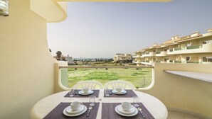 Ein Balkon mit Tisch für zwei Personen, mit Blick auf eine Wohngegend und ein Gewässer.