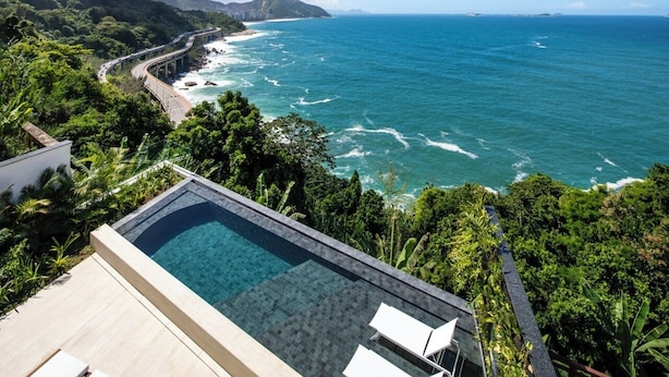 A pool with a view of the ocean and a road running parallel to the coast.