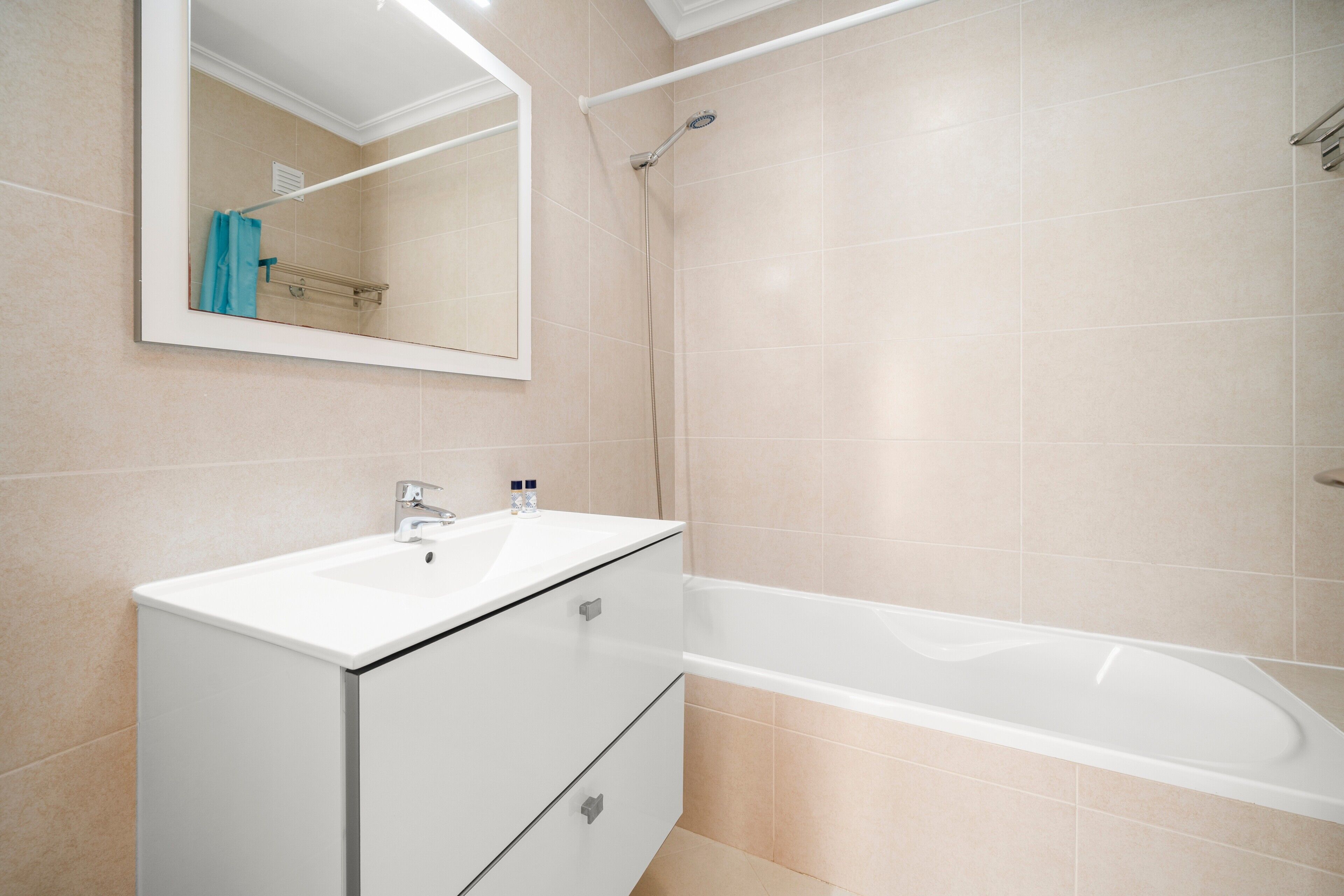 A bathroom with a white sink, mirror, and bathtub.