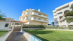 A multi-story hotel with balconies, a paved entrance, and a well-maintained lawn. - 1-Bedroom Apartment with Shared Pool, Wi-Fi, and Air Conditioning (Armação de Pêra)