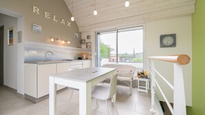 A modern kitchen with a dining area, a view through the window, and a 'RELAX' sign on the wall. - Apartment "Le clos du pont" with Lake View, Shared Pool and Wi-Fi (THEIX-NOYALO)