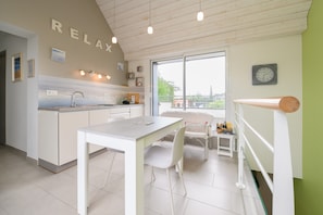 Una cocina moderna con comedor, vista por la ventana y un cartel con la palabra 'RELAX'.