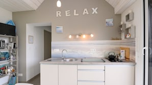 A kitchen with a sink, a kettle, and a 'RELAX' sign on the wall. - Apartment "Le clos du pont" with Lake View, Shared Pool and Wi-Fi (THEIX-NOYALO)