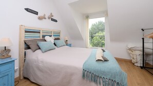 Un dormitorio con cama, mesita de noche, ventana y armario.
