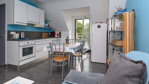 Una cocina moderna con armarios blancos, una mesa de comedor con sillas y un balcón con vistas.