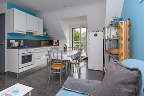 Una cocina moderna con armarios blancos, una mesa de comedor con sillas y un balcón con vistas.