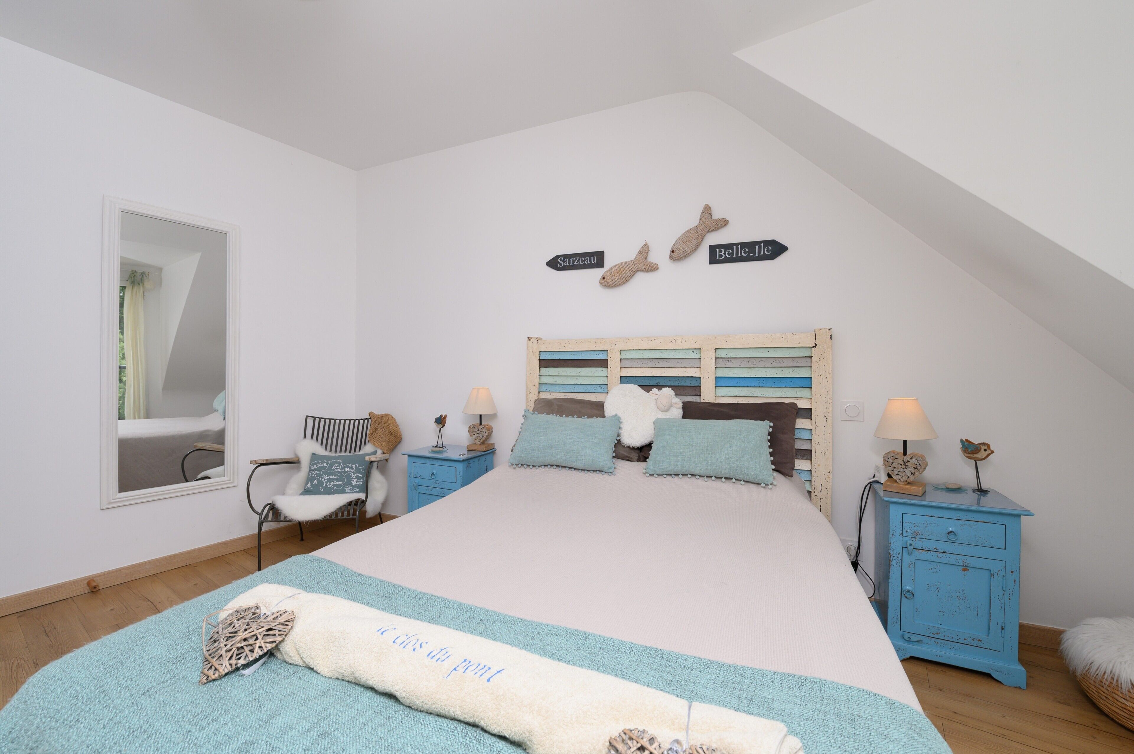 Une chambre à coucher comprenant un lit, une chaise, une table de chevet et un panneau fixé au mur.