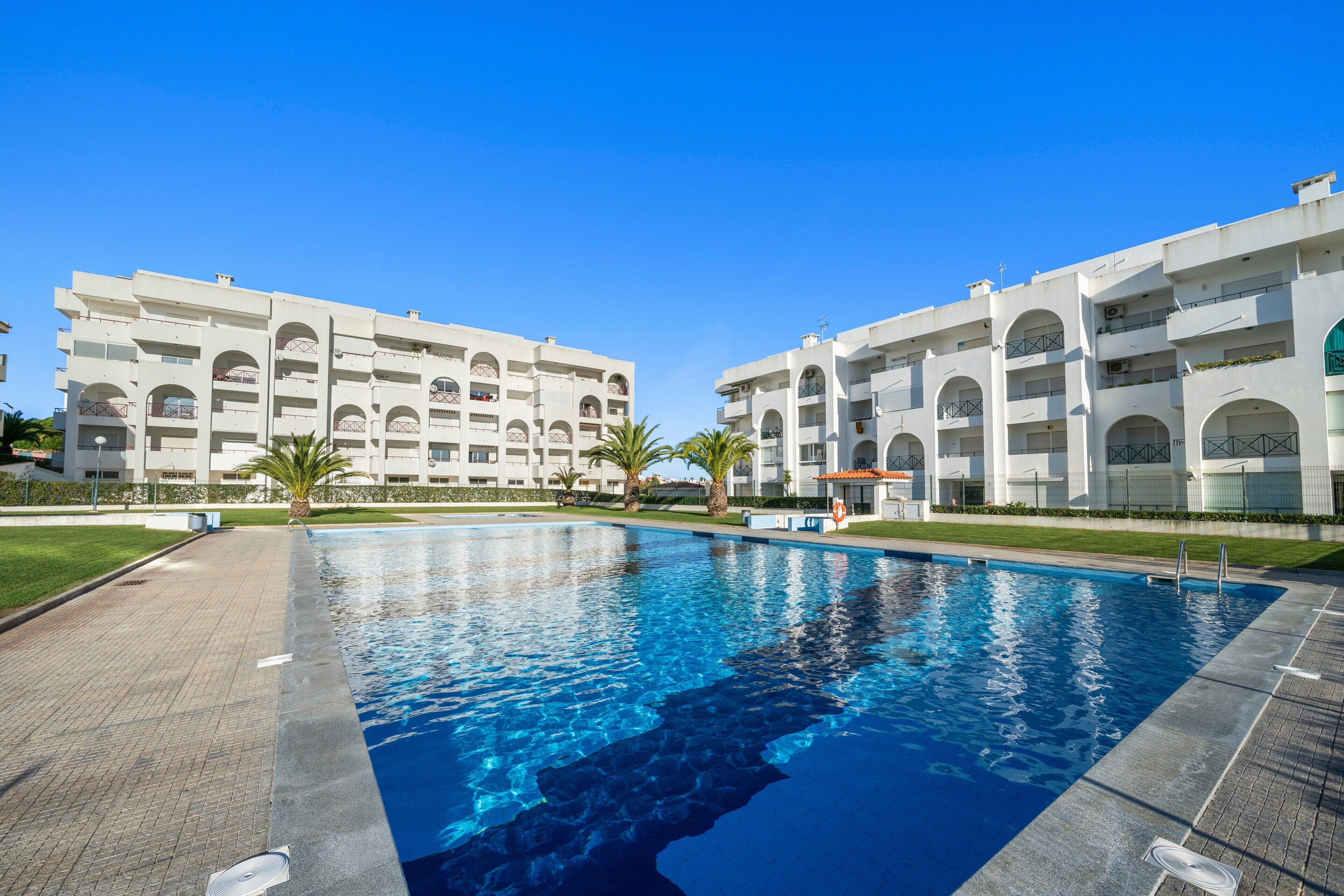 A swimming pool surrounded by a modern building with multiple balconies.