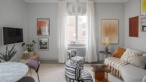 A modern living room with a sofa, armchair, and a dining table with chairs. - Stylish 2BR Apartment in Central Sundbyberg (Sundbyberg)