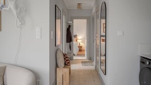 A hallway with a sofa, a stone sculpture, and a washing machine. - Stylish 2BR Apartment in Central Sundbyberg (Sundbyberg)