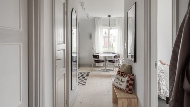 A hallway leading to a dining area with a checkered floor, a round table, and chairs. There is a bench with a cushion and a framed picture on the wall. - Stylish 2BR Apartment in Central Sundbyberg (Sundbyberg)