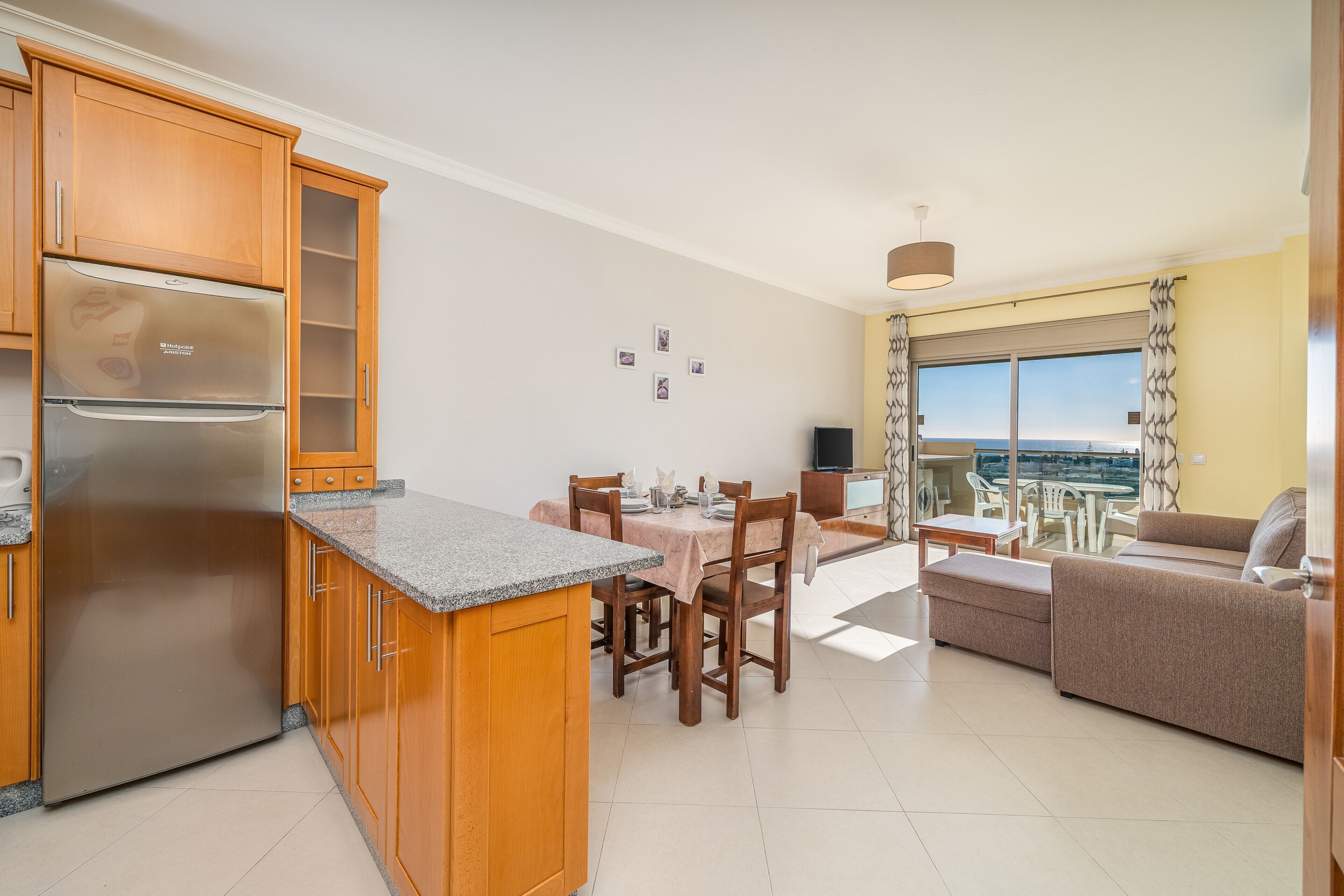 A modern kitchen with a built-in refrigerator, wooden cabinets, and a dining area with a table and chairs.