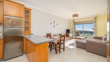 A modern kitchen with a built-in refrigerator, wooden cabinets, and a dining area with a table and chairs.