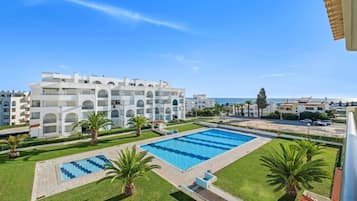 A hotel with a swimming pool, palm trees, and a view of the sea.