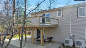 Une maison à deux étages dotée d’une terrasse, de meubles de jardin et de climatiseurs.