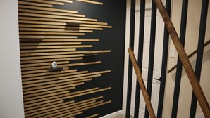 Un intérieur moderne avec un mur rayé noir et blanc, un motif de lattes en bois et un escalier doté de rampes en bois.