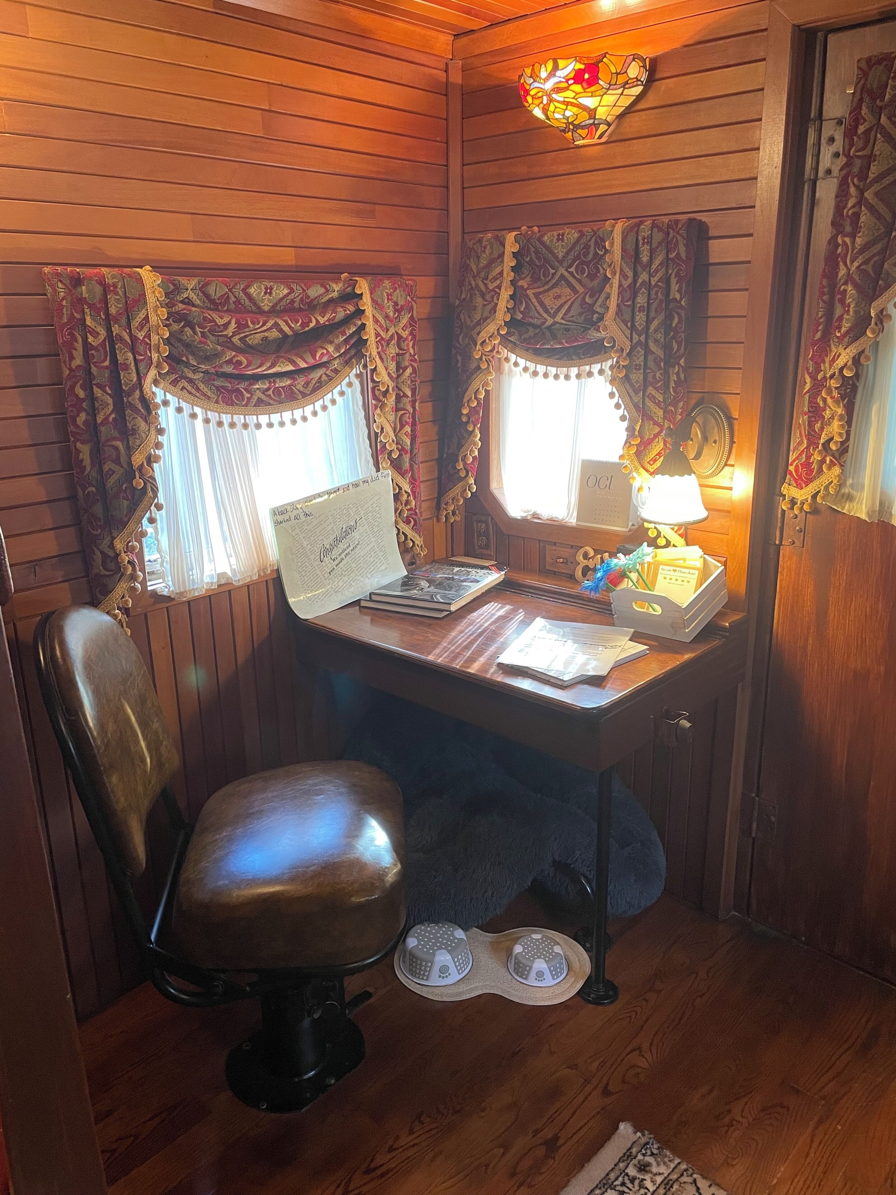 A wooden-paneled room with a desk, chair, and a small pet bed.