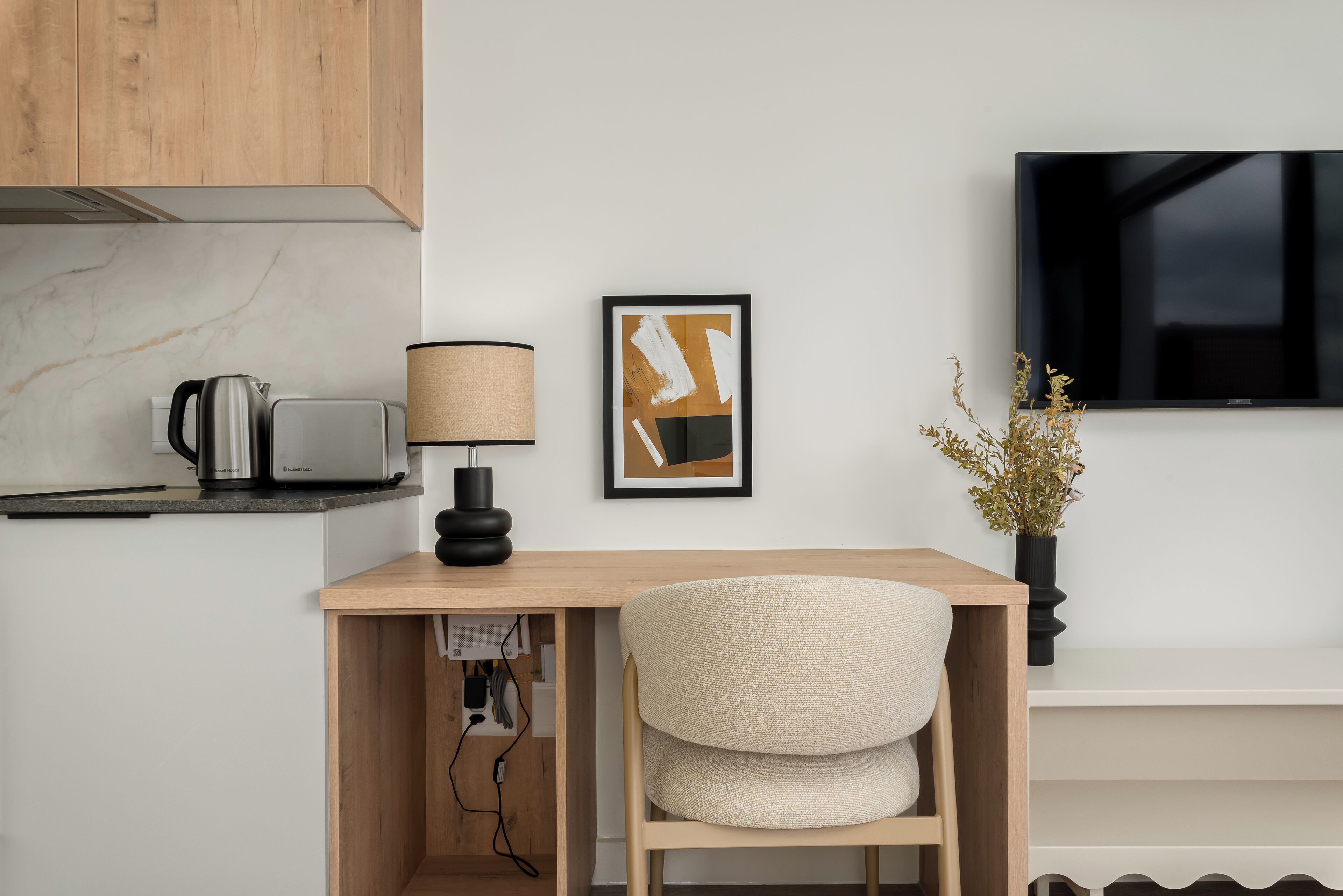 Una cucina moderna con un piano di lavoro in legno, un bollitore, una lampada e un quadro astratto incorniciato.