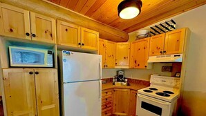 Une cuisine avec des meubles de rangement en bois, un réfrigérateur blanc, une cuisinière et un four à micro-ondes.