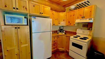 Une cuisine avec des meubles de rangement en bois, un réfrigérateur blanc, une cuisinière et un four à micro-ondes.