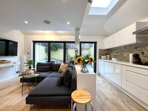 A modern living room with a sofa, a small table, and a vase of sunflowers. - The Secret Garden Fulham (London)