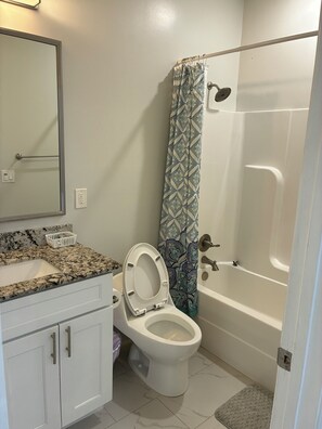 A bathroom with a toilet, sink, and bathtub. - Anchor's Away 2 Bed Apt. (Biloxi)