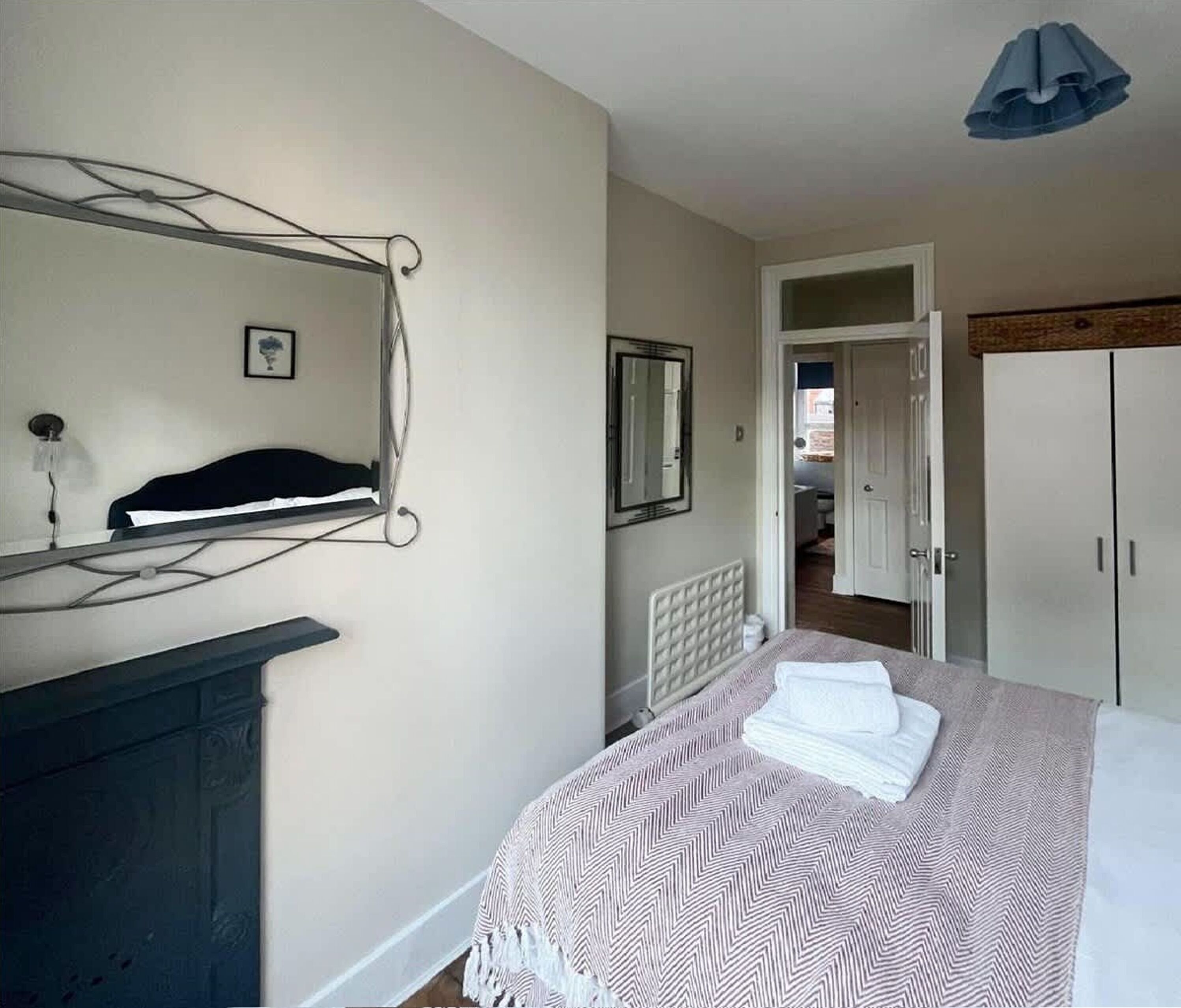 A bedroom with a bed, a dresser, a mirror, and a door leading to another room.