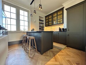 Una cocina moderna con una isla central, taburetes de madera y un ventanal que proporciona luz natural.