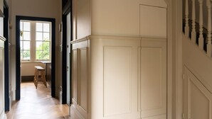 A hallway with a wooden floor, a window with a view of greenery, and a door with a white trim. - Melody Apartament in Greater London (London)