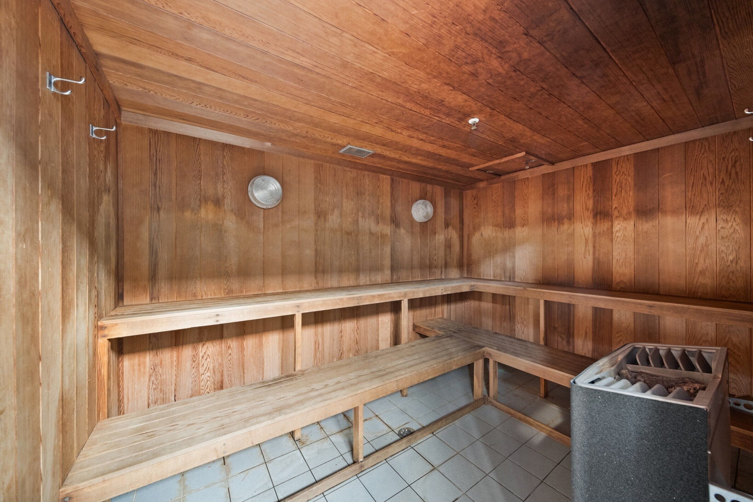 A sauna with wooden benches and a trash bin.