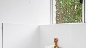 Wasruimte met een Samsung wasmachine, een houten snijplank, een vaas met witte bloemen en een kleine schaal.